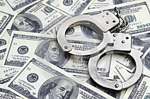 Police handcuffs lie on a lot of dollar bills. The concept of illegal possession of money, illegal transactions with US dollars.