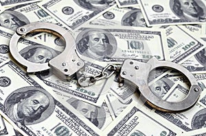 Police handcuffs lie on a lot of dollar bills. The concept of illegal possession of money, illegal transactions with US dollars.