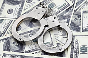 Police handcuffs lie on a lot of dollar bills. The concept of illegal possession of money, illegal transactions with US dollars.