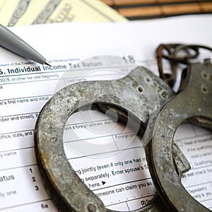 Police handcuffs lie on the tax form 1040. The concept of proble