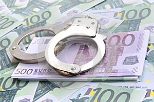 Police handcuffs lies on a set of green monetary denominations o