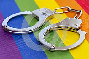 Police handcuffs rest on a colorful LGBT flag. Concept: criminalization, ban in Russia.