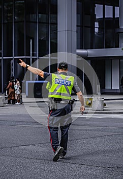 Police man is directing traffic during the rush hour in down town Toronto. Police man regulating traffic on city street