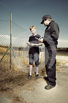 Police man questioning a teenage boy in fields