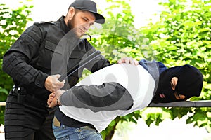 Police officer with baton arresting masked criminal