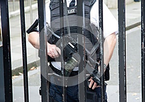 Police officer in a defensive position, equipped with a sidearm, in front of a chain-link fence