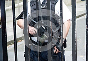 Police officer in a defensive position, equipped with a sidearm, in front of a chain-link fence photo