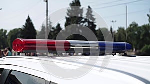 A police officer flashes a light on the roof of a patrol car. Close up
