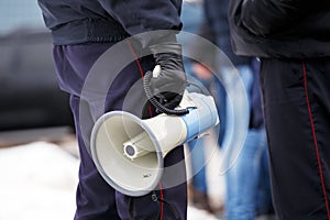 police officer holding loudspeaker megaphone outdoors, close-up