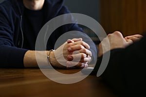 Police officer interrogating criminal in  at desk indoors