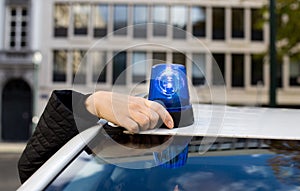 Police officer mounting rotating emergency light on a car