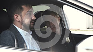 Police officer sitting in car with detainee man