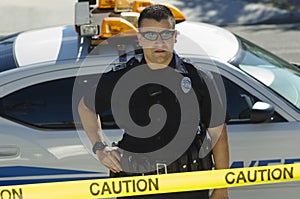 Police Officer Standing Behind Caution Tape