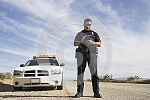 Police Officer Taking Notes In Front Of Car