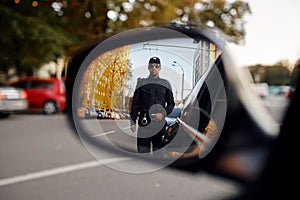 Police officer, view through car rear view mirror