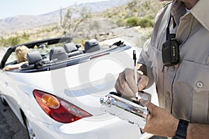 Police Officer Writing Traffic Ticket To Woman Sitting In Car photo