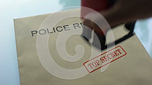 Police report top secret, hand stamping seal on folder with important documents