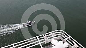 Police or Sheriff boat following a large cruise liner in the ocean
