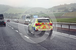 Police siren flashing blue lights on motorway in bad weather conditions