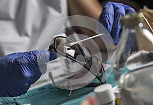 Police specialist examines pin of glasses stained with blood belonging to the victim of murder