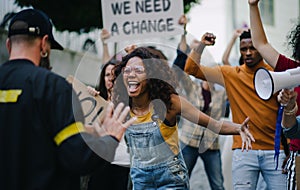 Police stopping group of people activists with raised fists protesting on streets, BLM demonstration concept.