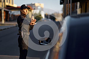 Police woman using walkie-talkie controlling road traffic