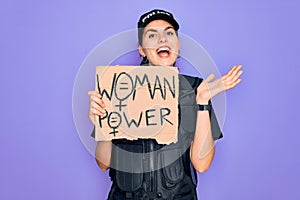 Police woman wearing security bulletproof vest uniform holding woman power protest cardboard very happy and excited, winner