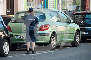 Police woman writing a minutes for a parked car