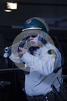 Policeman Aiming Rifle While Standing In Front Of Car