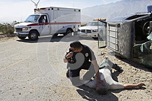 Policeman Checking Pulse Of Car Crash Victim