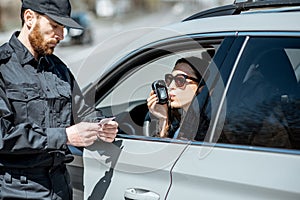 Policeman checking woman driver for alcohol intoxication