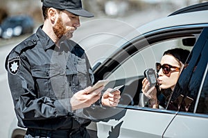 Policeman checking woman driver for alcohol intoxication