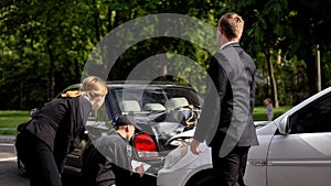 Policeman examining car accident and making notes, male and female drivers road