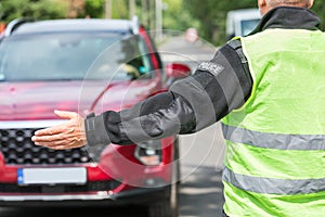 Policeman extends his hand to stop a red car