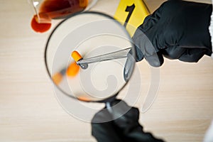 A policeman looks through a magnifying glass at the evidence at the crime scene. The crime scene of poisoning and overdosing