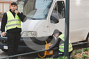 Policeman during the patrol puts a blockade on the wheel of a car