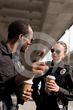 policeman pointing somewhere while drinking coffee to go