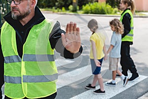 Policeman in a reflective vest raises his hand to stop the car