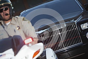 Policeman Sitting On Motorbike With Car In Background