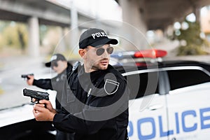 Policeman in sunglasses holding gun and