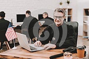 Policeman Works On Laptop In A Police Station.