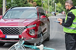 Policeman writes a ticket standing in front of a car that hit a cyclist on a pedestrian lane