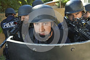Policemen Aiming Guns While Standing Behind Shield photo