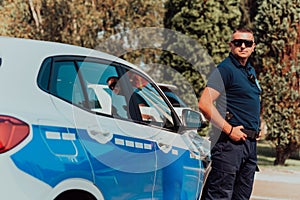 A policeofficer patrols the city. A police officer with sunglasses patroling in the city with an official police car