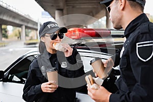 Policewoman eating burger and holding coffee