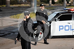 Policewoman with gun using walkie talkie