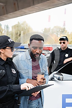 Policewoman holding clipboard near african american