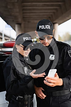 Policewoman in sunglasses pointing at smartphone