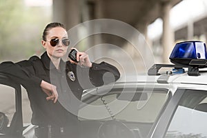 policewoman in sunglasses talking on portable radio