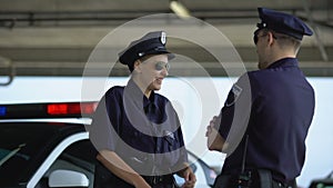 Policewoman talking to her mate and laughing standing near patrol car, break